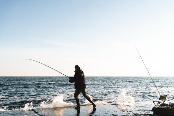 An angler fights a fish at the water's edge